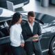 Filling the documents. Female customer and modern stylish bearded businessman in the automobile saloon.